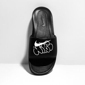 Nike Men’s Victori One Slides with white graffiti-style print and “Swish”.
